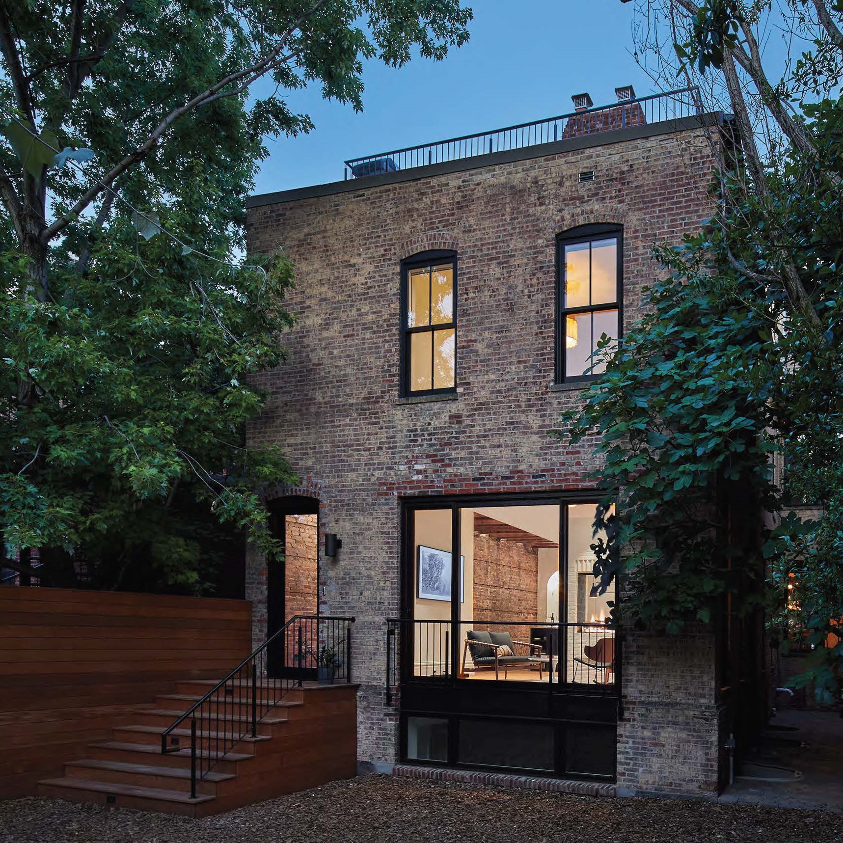 Photo of back side of rowhouse with white-washed brick and floor-to-ceiling windows