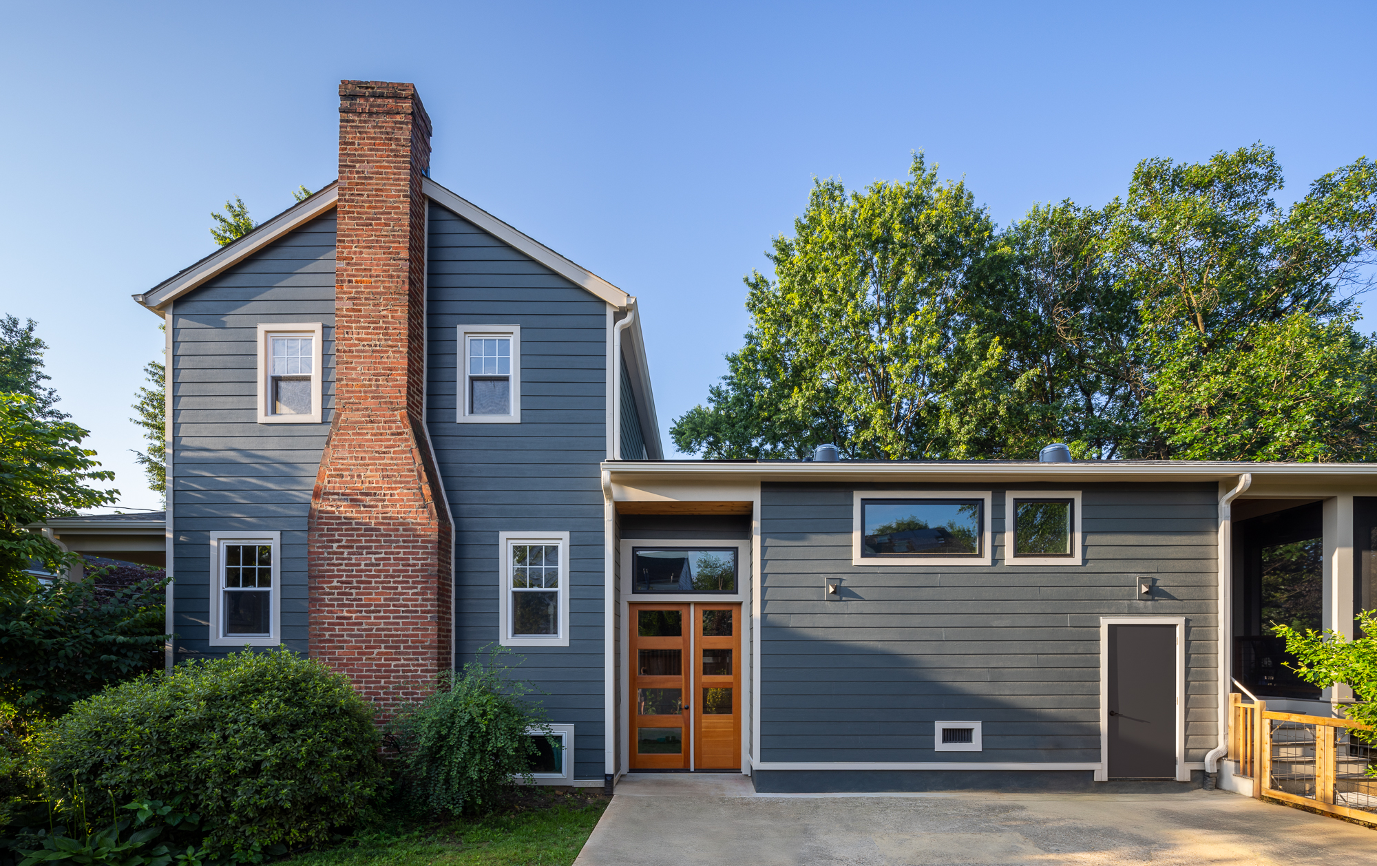 a gray with white trim single-family home with renovated existing section of home on left and new addition on the right side of image.